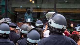 Students inside the Columbia University encampment look out the window over a sea of NYPD in riot gear. | Photo: Syndi Pilar/ZUMAPRESS/Newscom