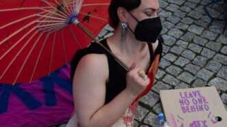 protester with red umbrella and a sign saying "leave no one behind | sex work is work" | Paul Zinken/dpa/picture-alliance/Newscom