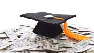 A mortarboard sits on a pile of U.S. hundred-dollar bills. | Steven Cukrov | Dreamstime.com