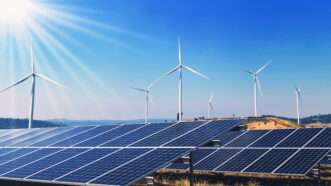 A field full of solar panels, with wind turbines in the distance. | Lovelyday12 | Dreamstime.com