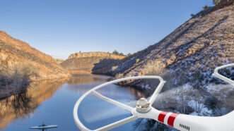 An overhead shot of the Horsetooth Reservoir near Fort Collins, Colorado, with a kayaker in the distance. An unmanned flying drone is visible in the extreme foreground. | Marek Uliasz | Dreamstime.com