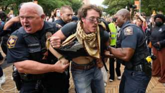 Police officers holding a protester by the arms | Photo: Jay Janner/USA Today Network